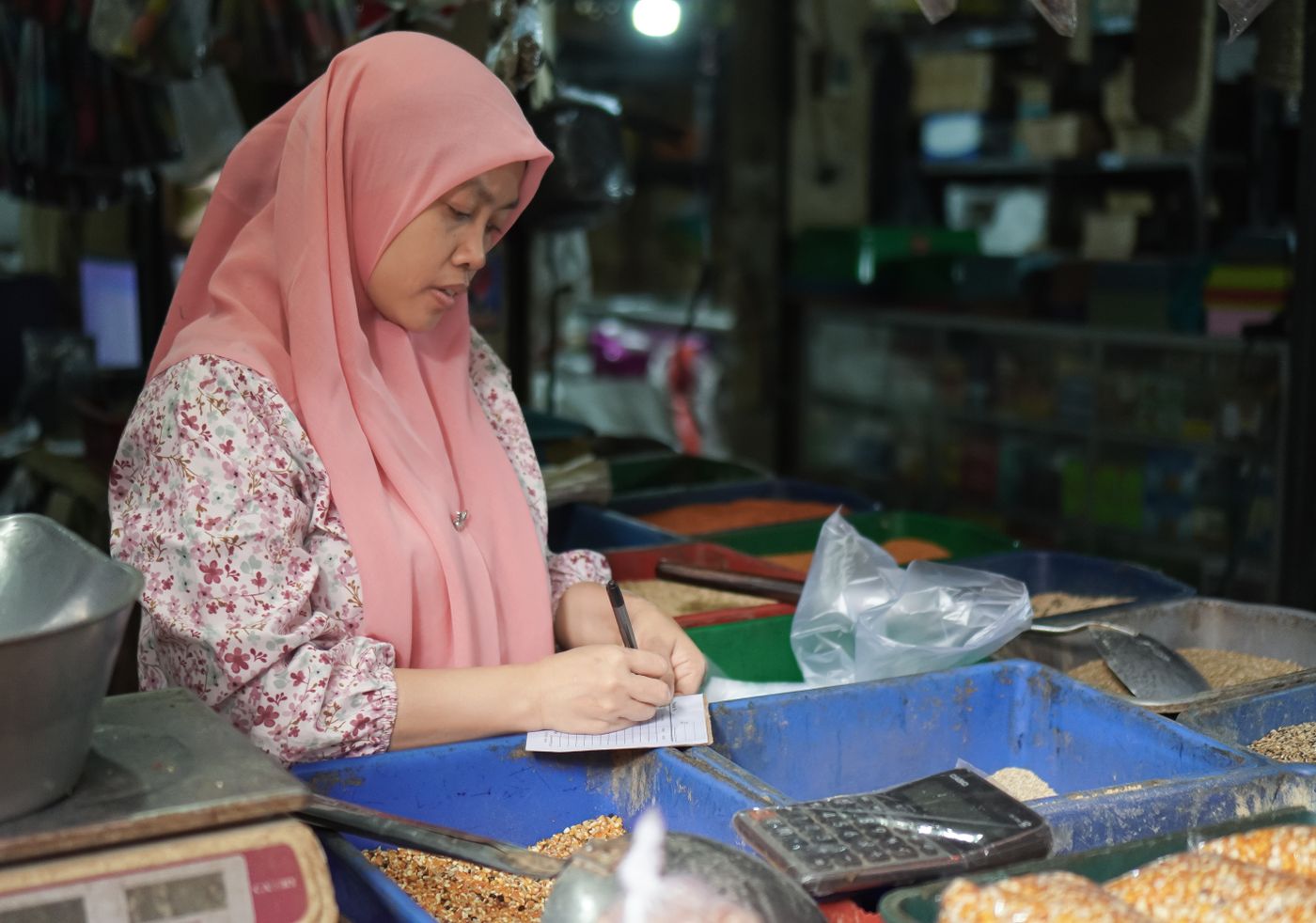 A Malaysian market owner working out her numbers